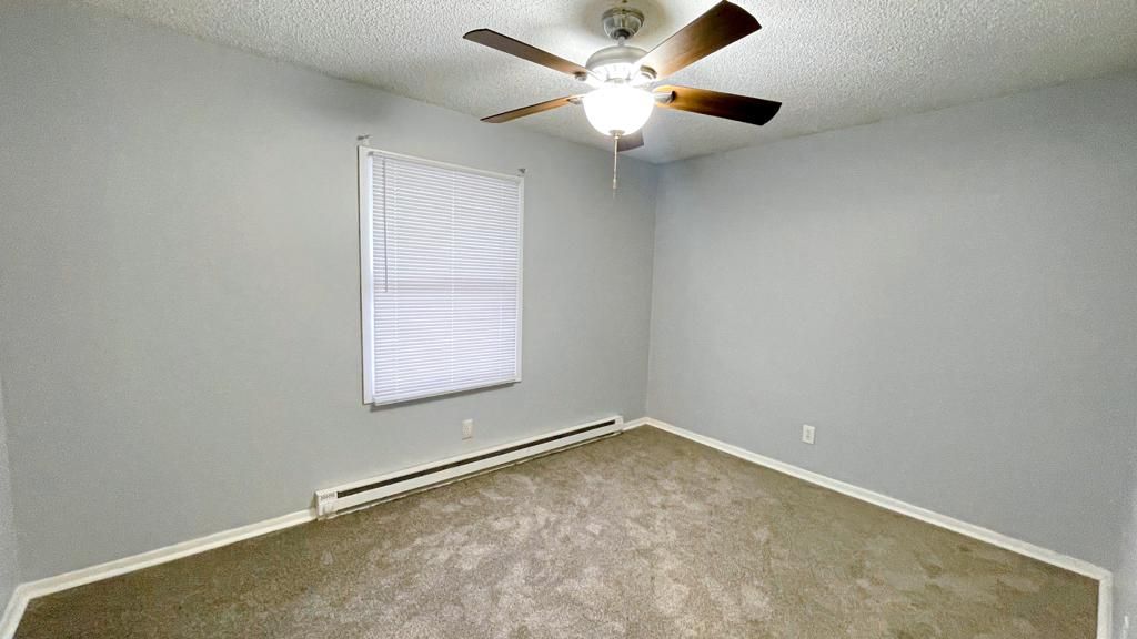 an empty bedroom with a ceiling fan and a window .