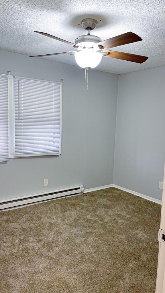 an empty bedroom with a ceiling fan and a window .