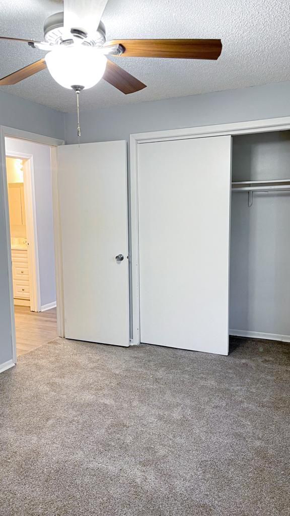 an empty bedroom with a ceiling fan and a closet .