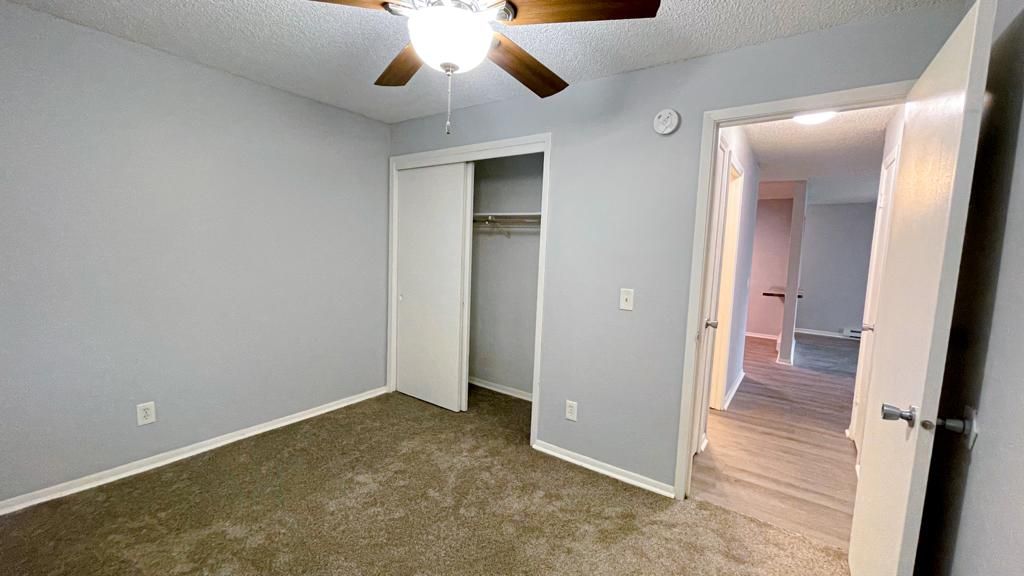 an empty bedroom with a ceiling fan and a closet .