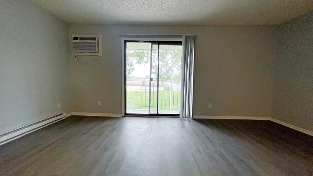 an empty living room with a sliding glass door and a balcony .