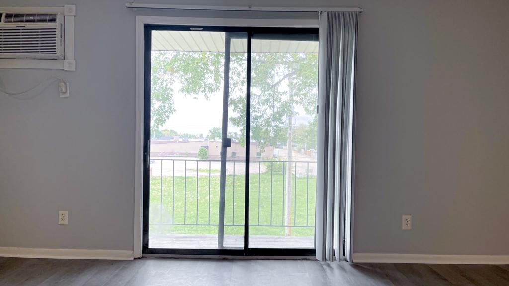 an empty living room with a sliding glass door leading to a balcony .