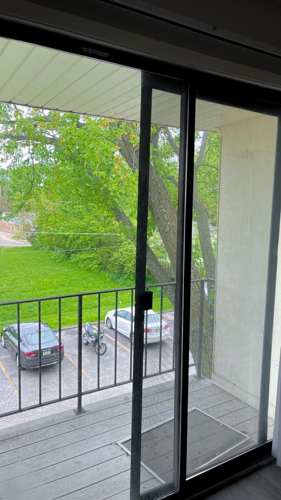 a sliding glass door leading to a balcony with a view of a parked car .