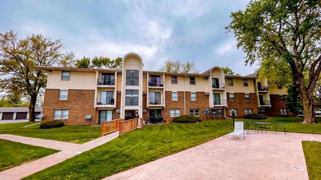 a large apartment building with a lush green lawn in front of it .