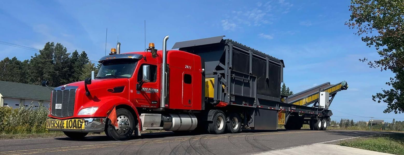A red semi truck is driving down a road with a trailer.