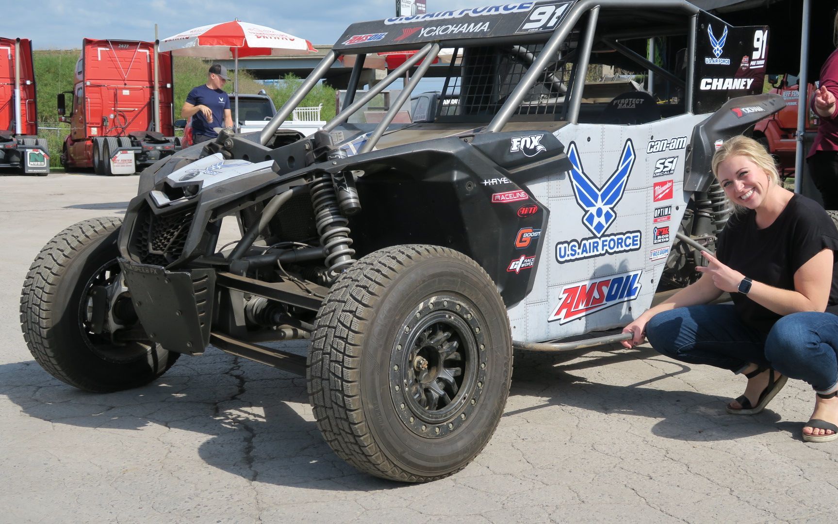 A woman is squatting next to a buggy that says air force on it.