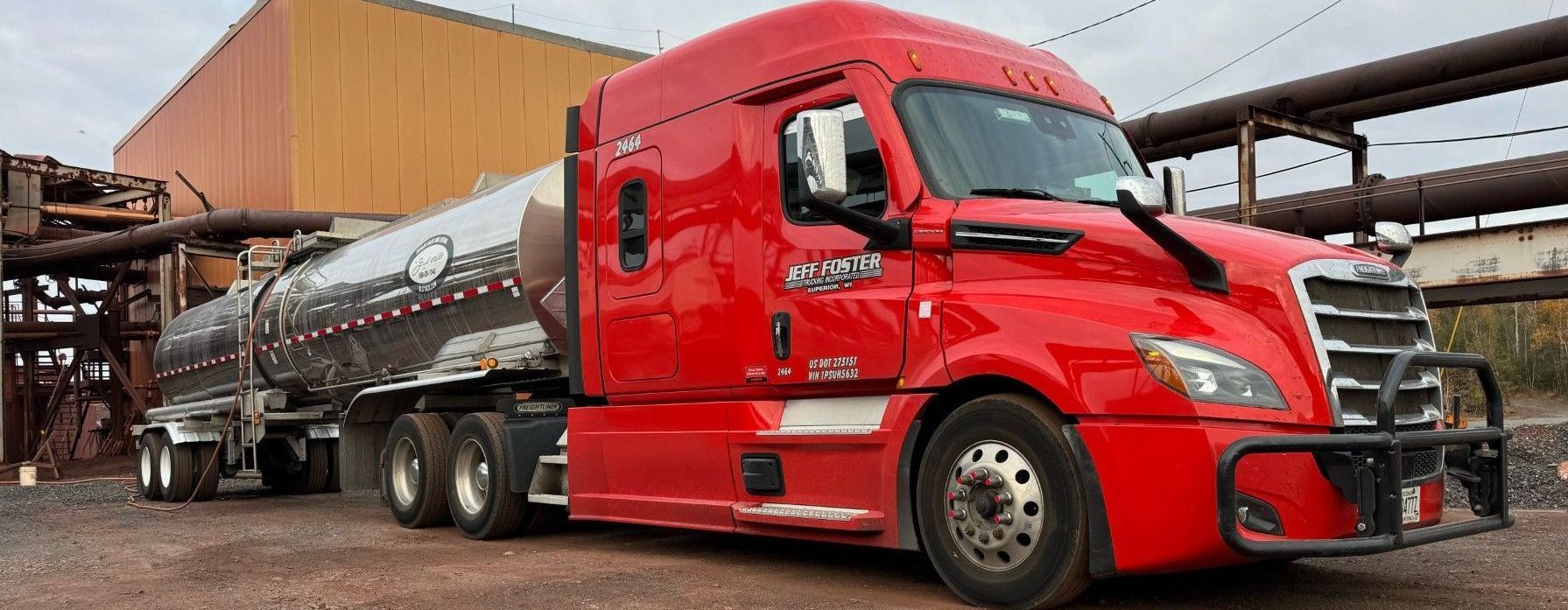 A red semi truck is parked in front of a building.