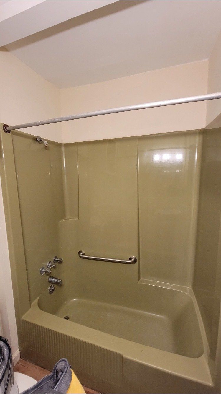 Beige bathtub and shower with sliding glass doors and chrome grab bar in a bathroom