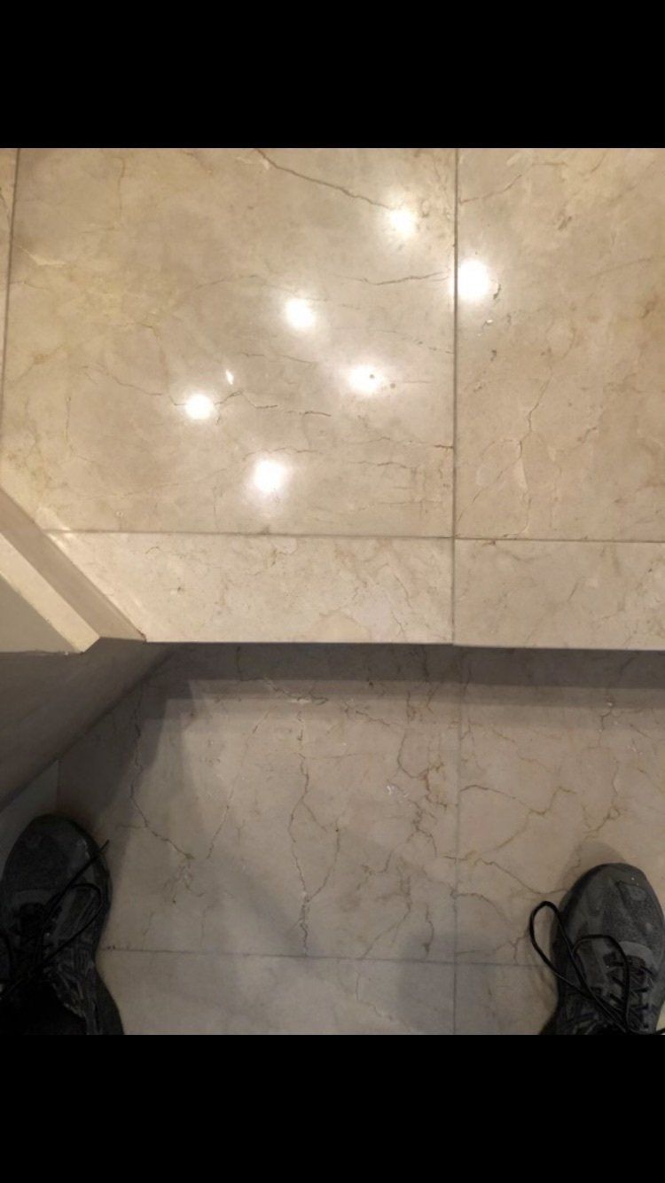 Marble-tiled floor with shoe tips visible at the bottom, viewed from above.