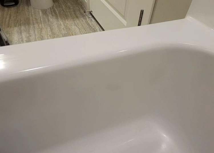 White bathtub in a bathroom with a tiled floor and cabinet visible in the background