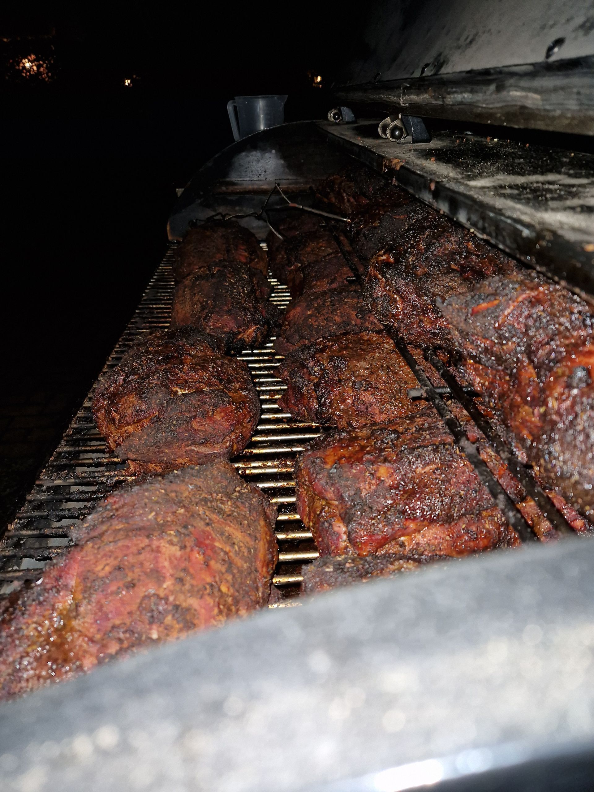 's Nachts liggen verschillende stukken gekruid vlees te garen op een metalen grillrooster.