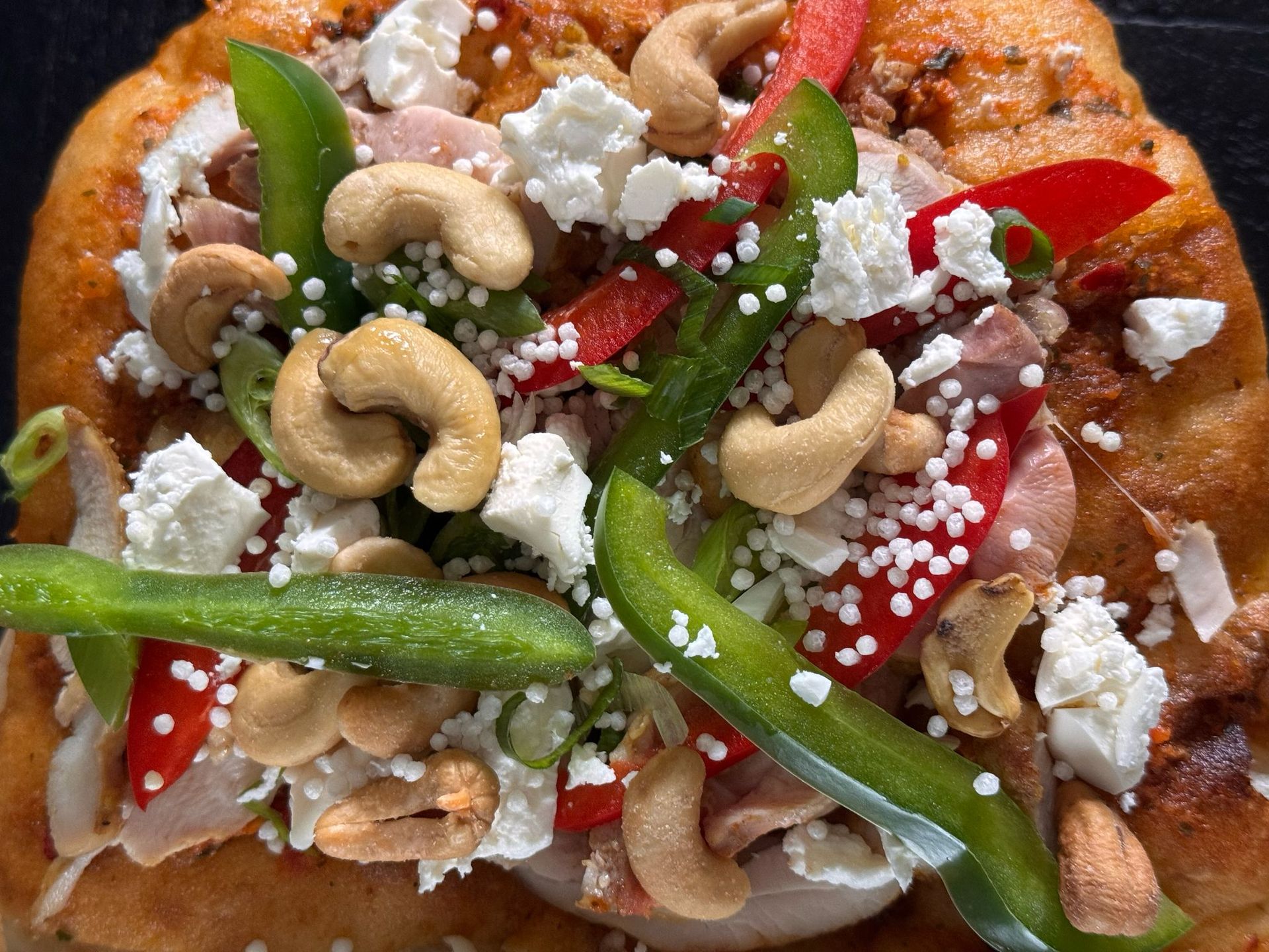 Platbrood belegd met groene paprika, rode paprika, cashewnoten en verkruimelde witte kaas.
