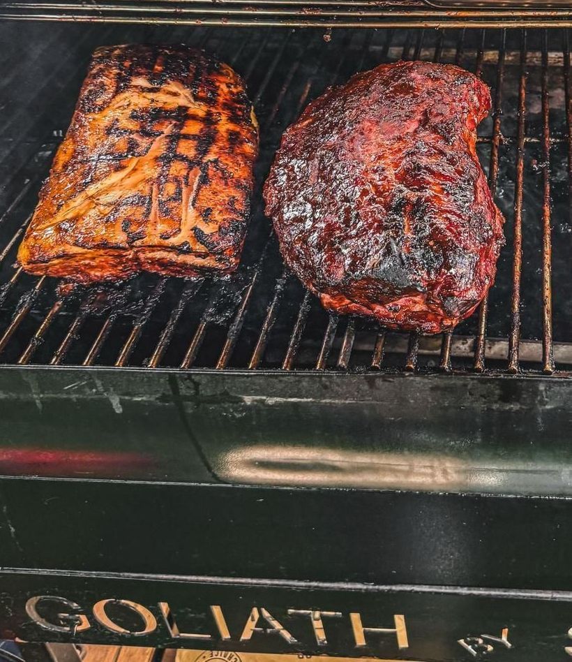 Twee stukken gekruid vlees liggen te grillen op een barbecue-rookrooster met het opschrift