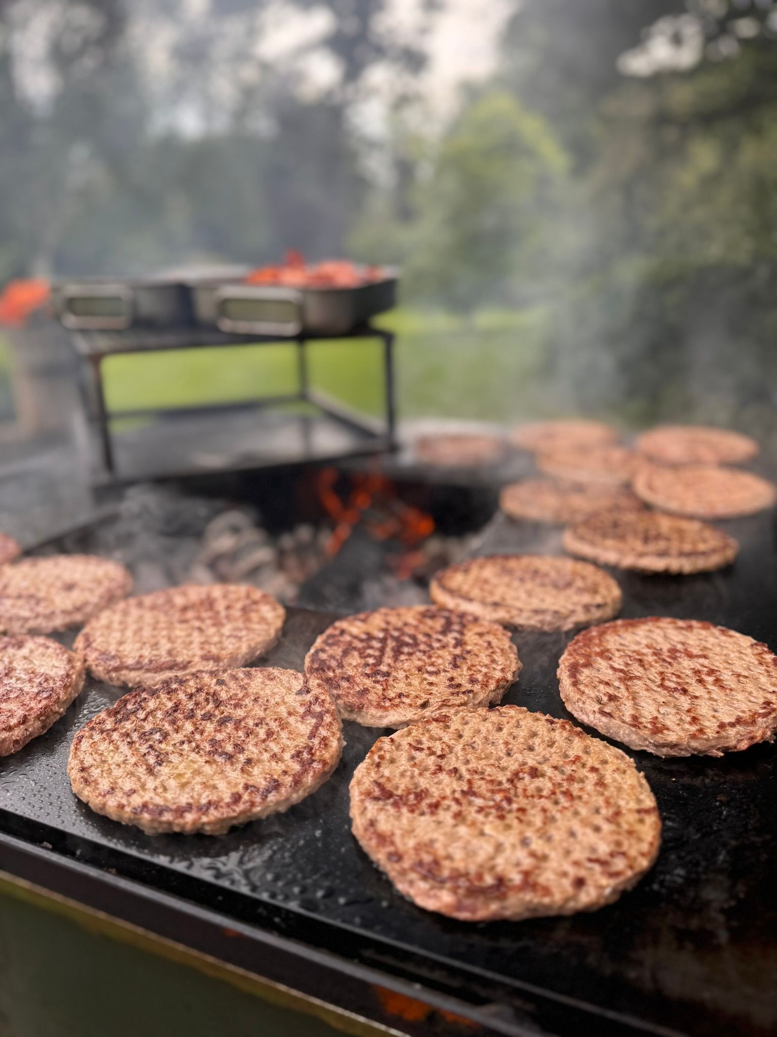 A bunch of hamburger patties are cooking on a grill.