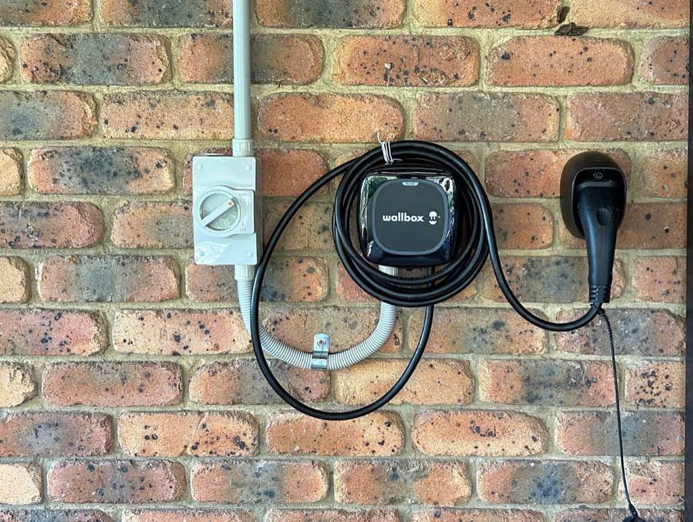 A Brick Wall With an Electric Vehicle Charger Attached to It — Ocean Air Electrical in Skennars Head, NSW