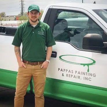 A man in a green shirt is standing in front of a truck.