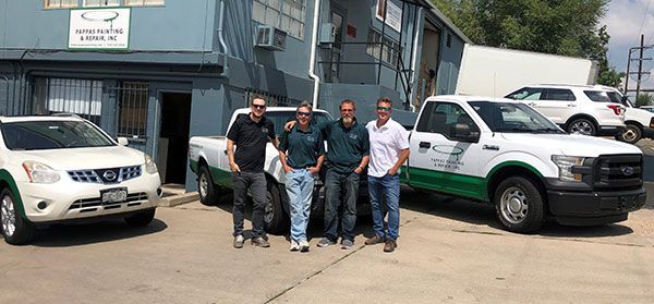 A group of men are posing for a picture in front of their trucks.