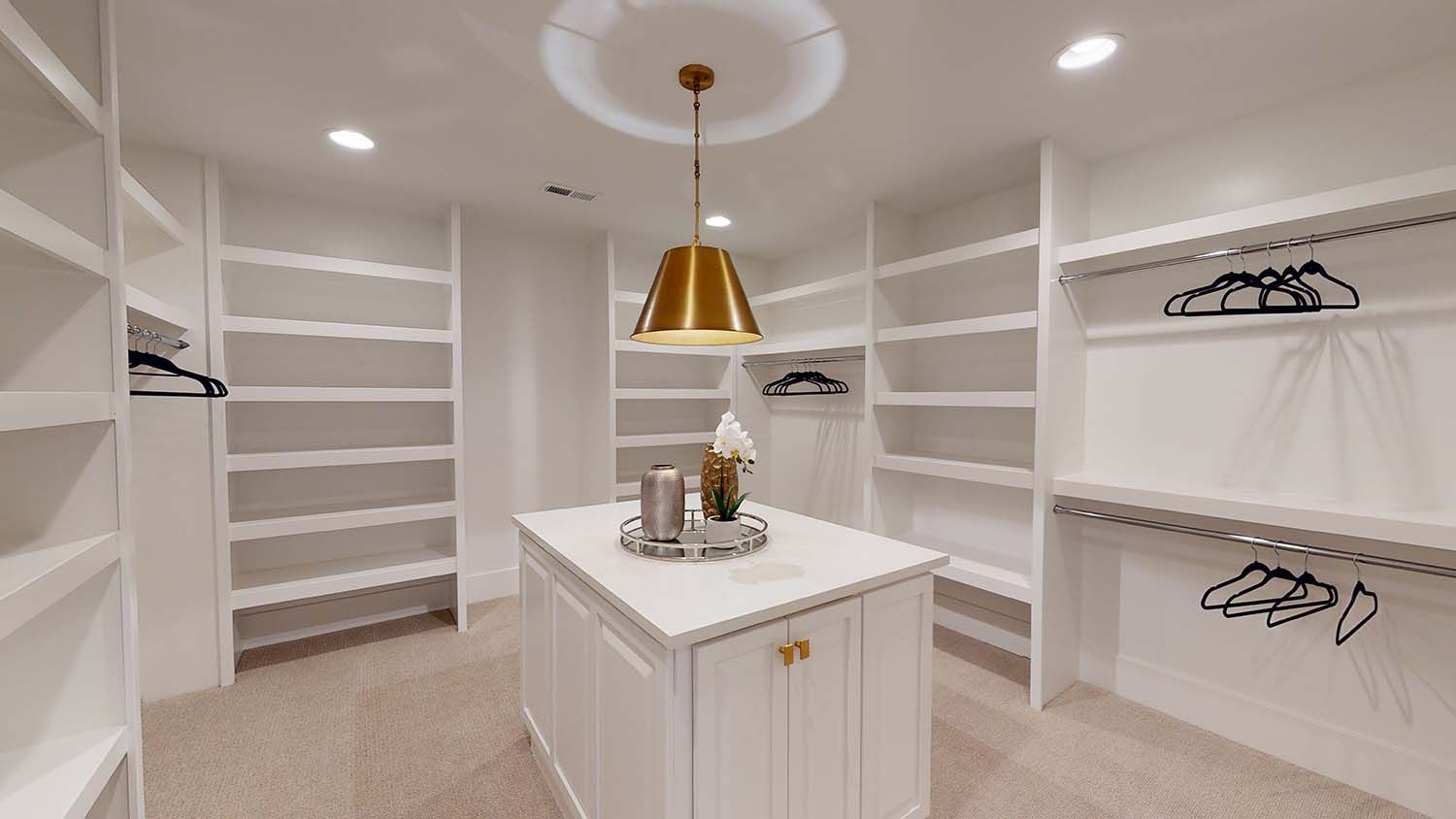 A walk in closet with a large island in the middle.