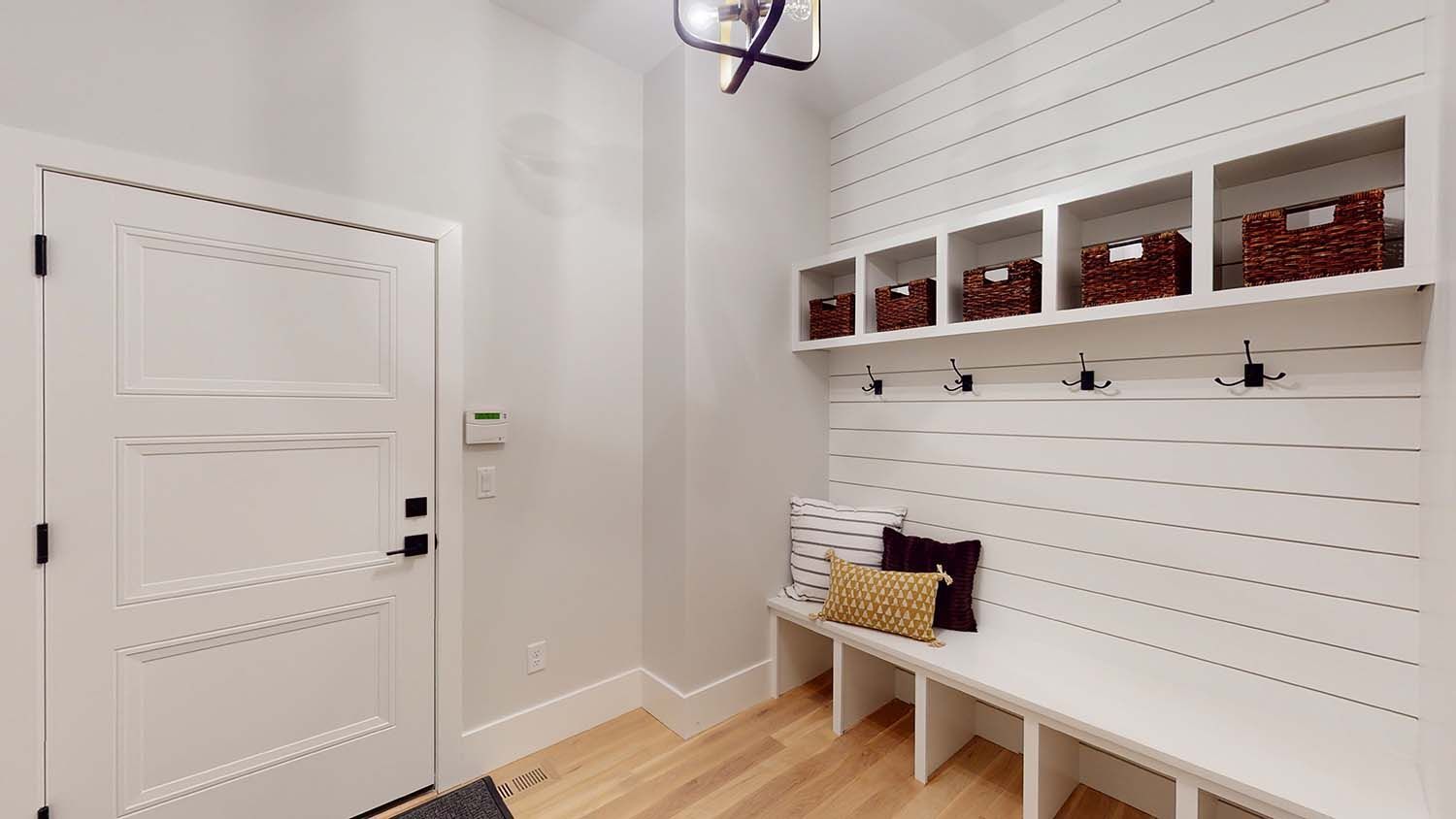 A mud room with a bench and hooks on the wall.