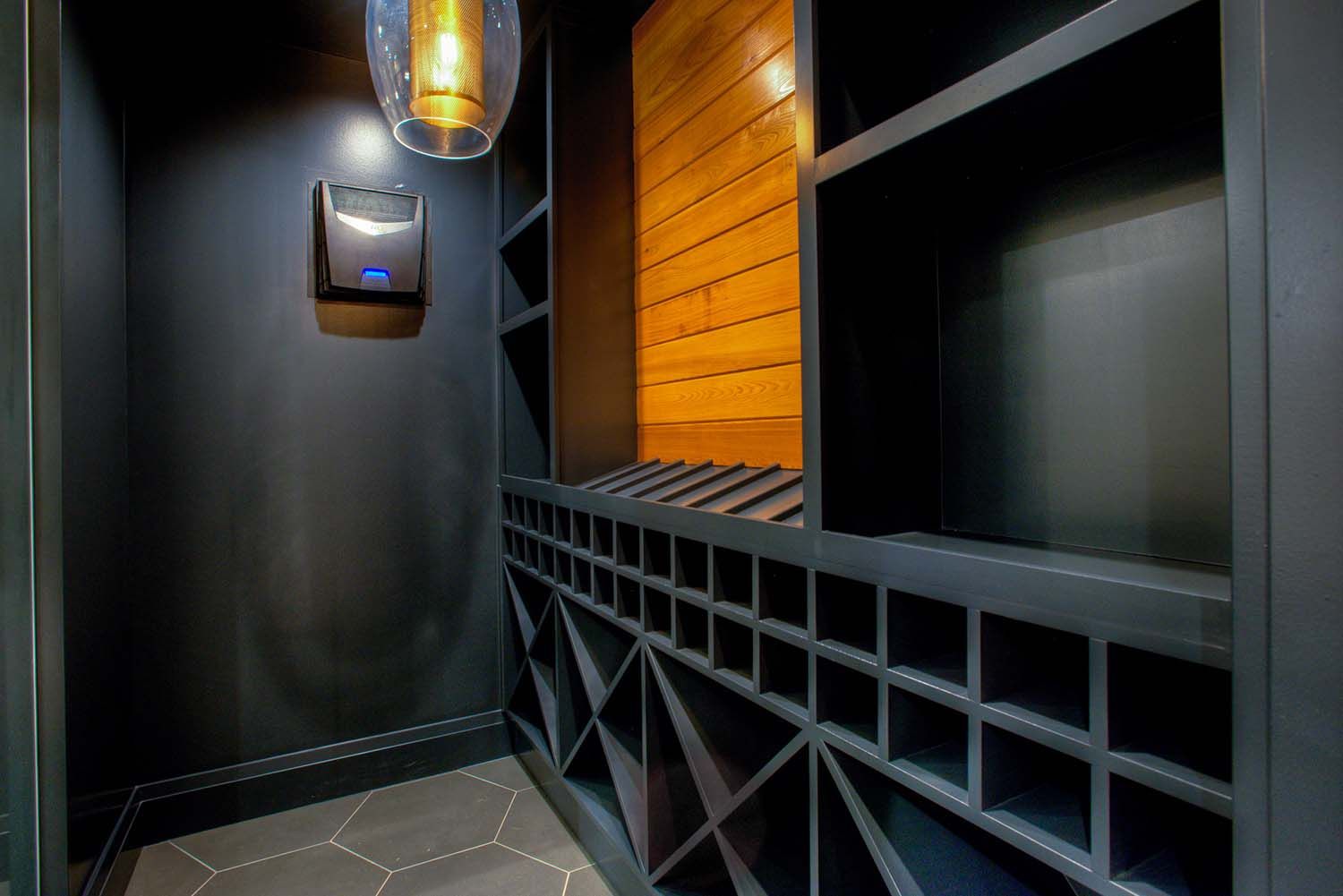 A wine cellar with lots of shelves and a light hanging from the ceiling.