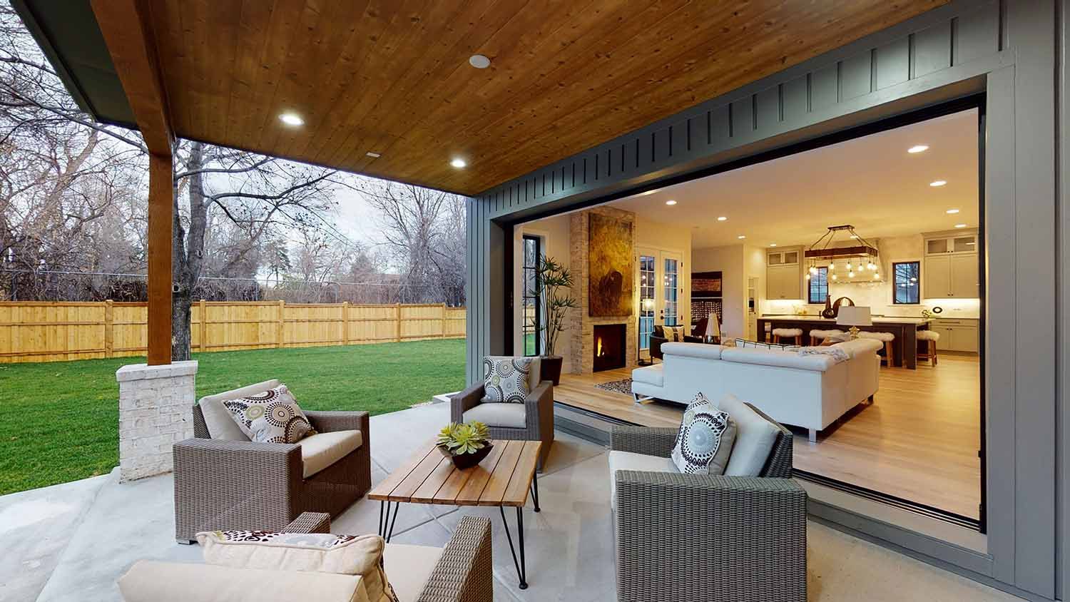 A patio with a lot of furniture and a sliding glass door leading to a living room.