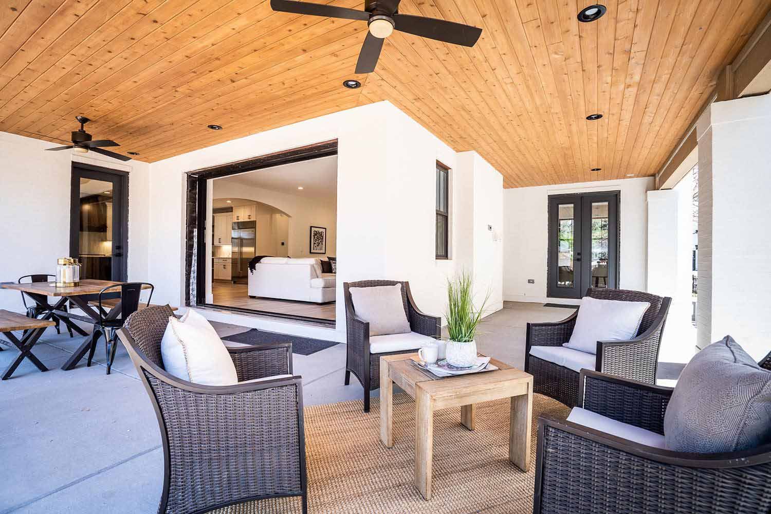A patio with chairs , a table and a ceiling fan.