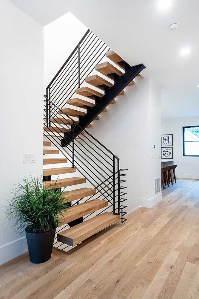 A wooden staircase with a black railing in a house.