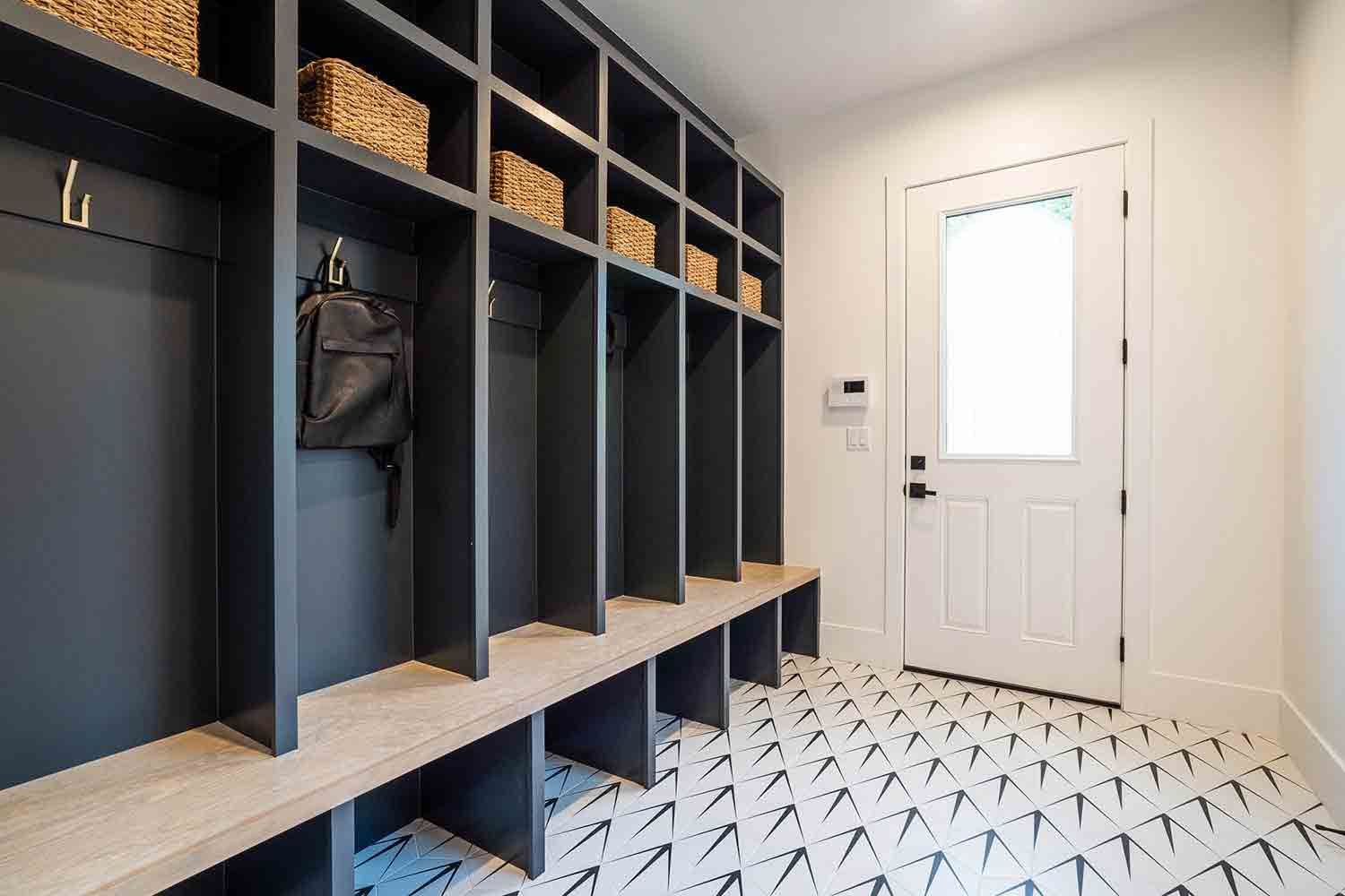 A mud room with lots of shelves and a bench in front of a door.