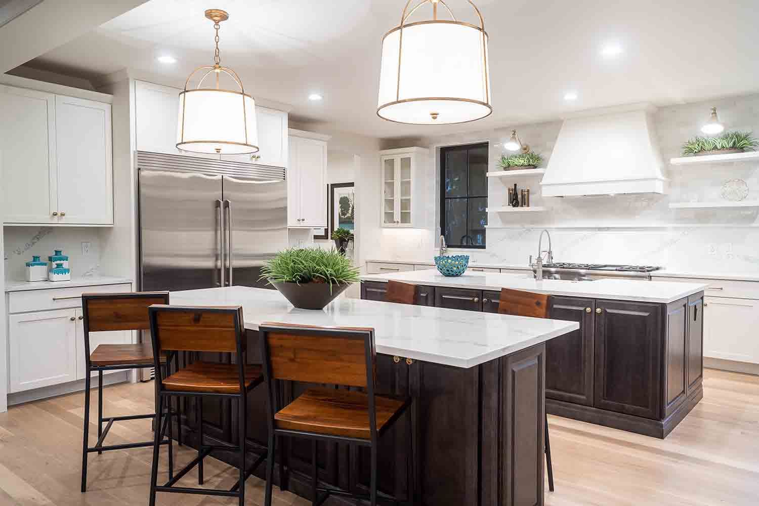 A kitchen with a large island , stainless steel appliances , white cabinets and wooden chairs.