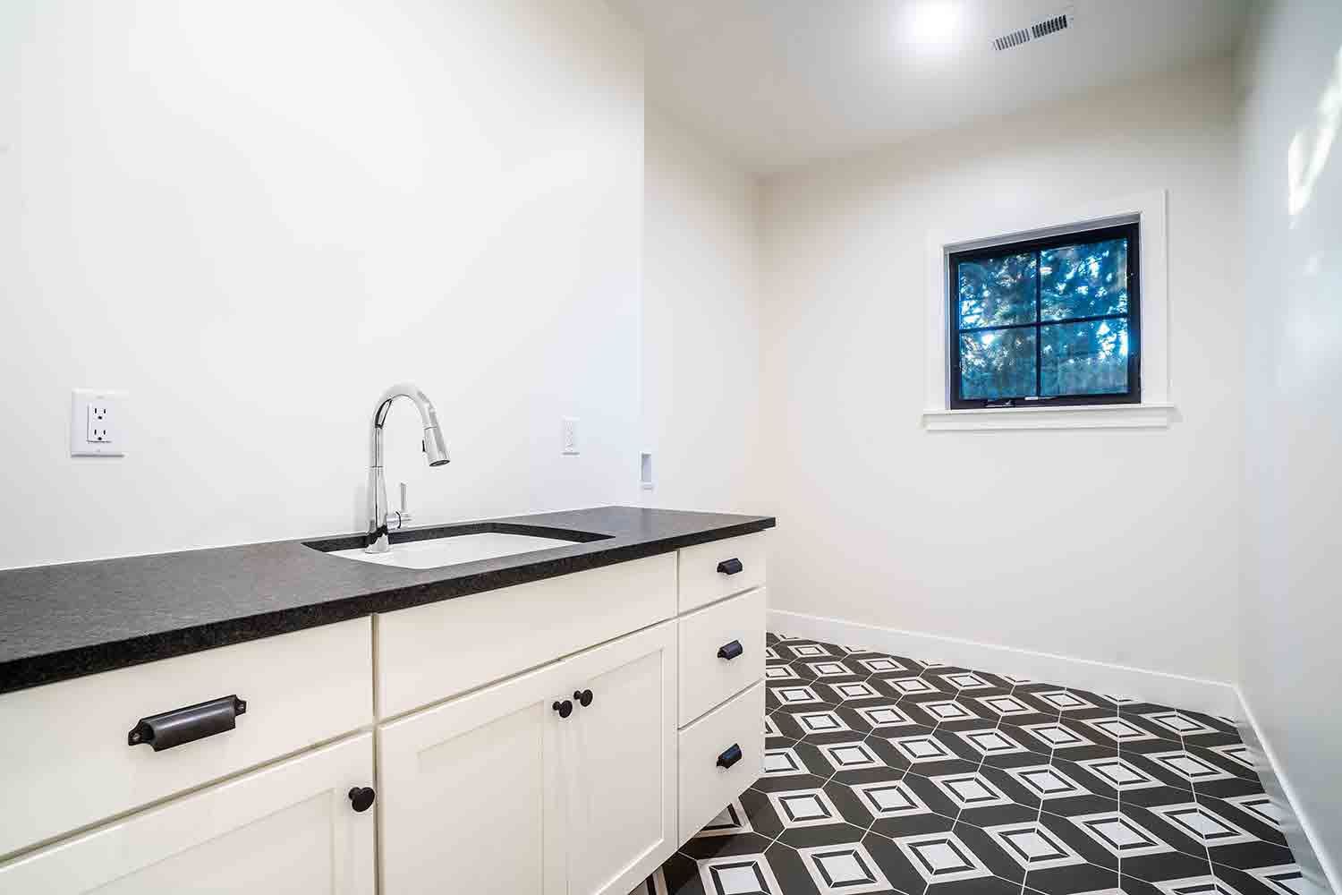 A kitchen with a sink , cabinets , and a window.