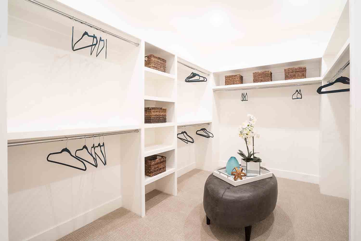 A walk in closet with a coffee table and ottoman.
