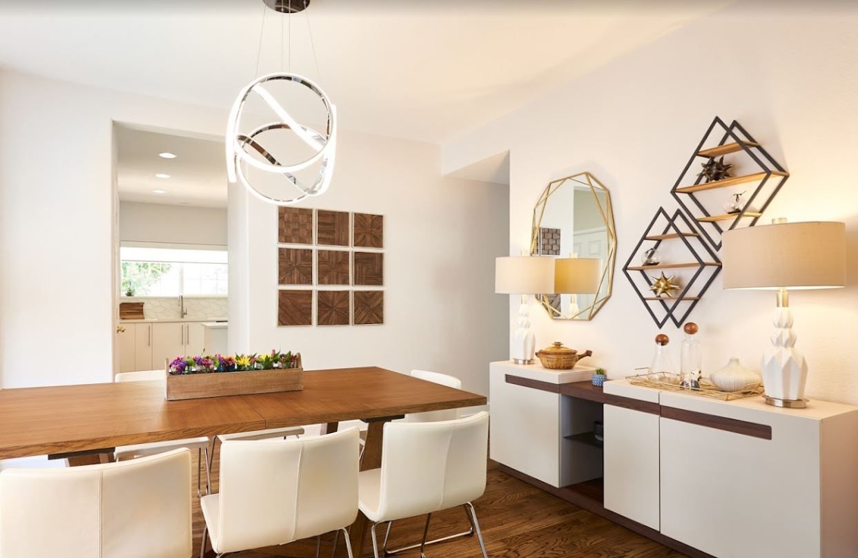 A dining room with a wooden table and white chairs.