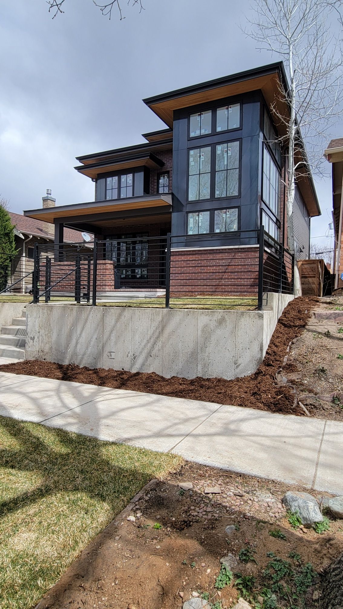 A large house is sitting on top of a hill next to a sidewalk.