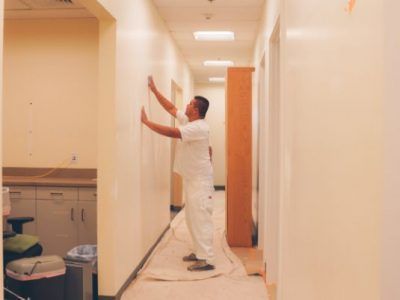 A man is painting a wall in a hallway.