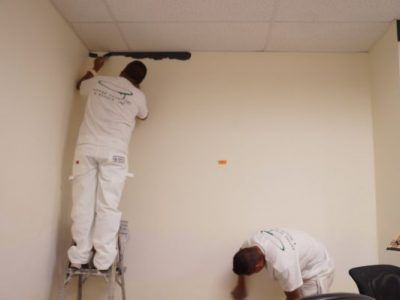 A man standing on a ladder painting a wall