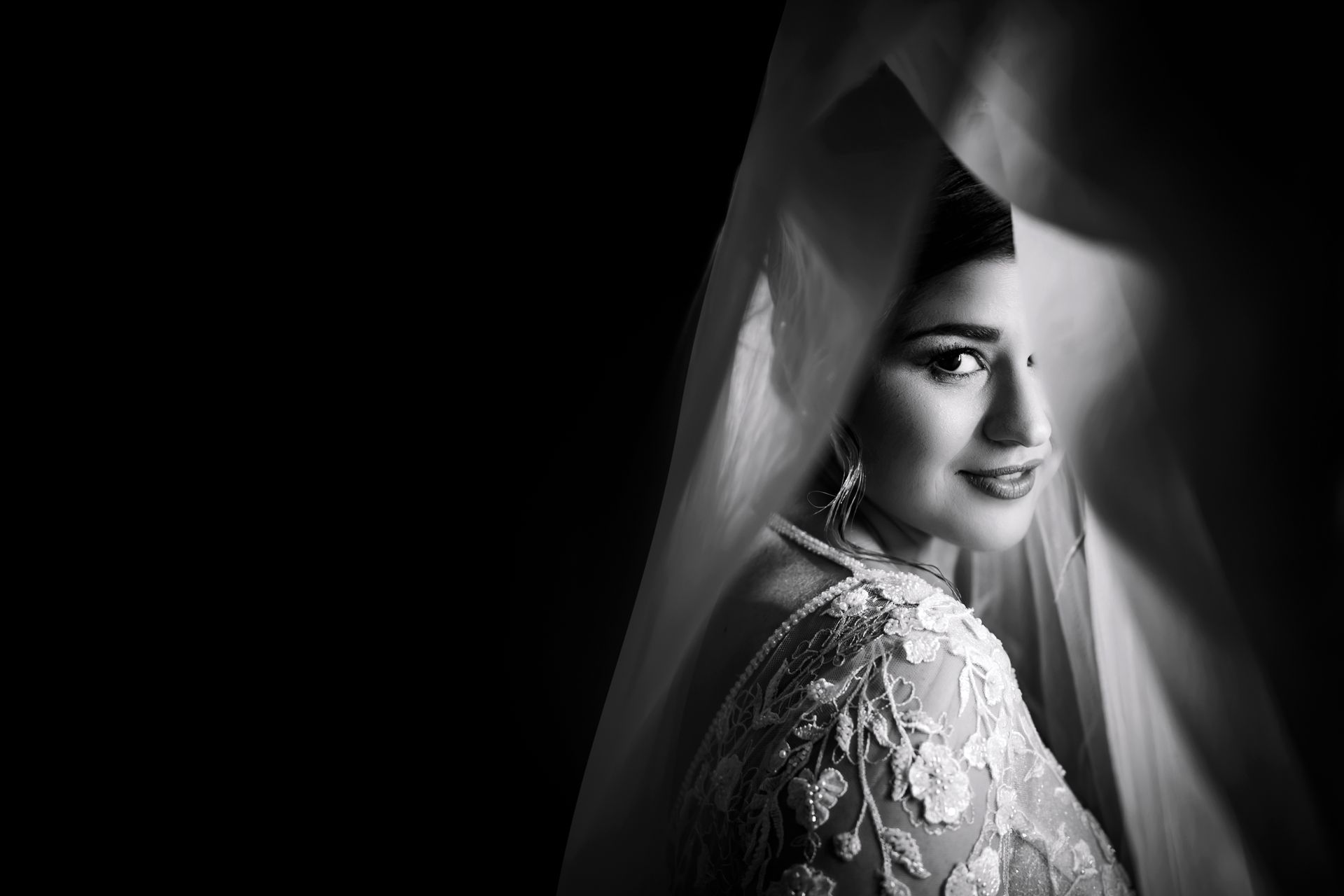 Una foto in bianco e nero di una sposa in abito da sposa e velo.
