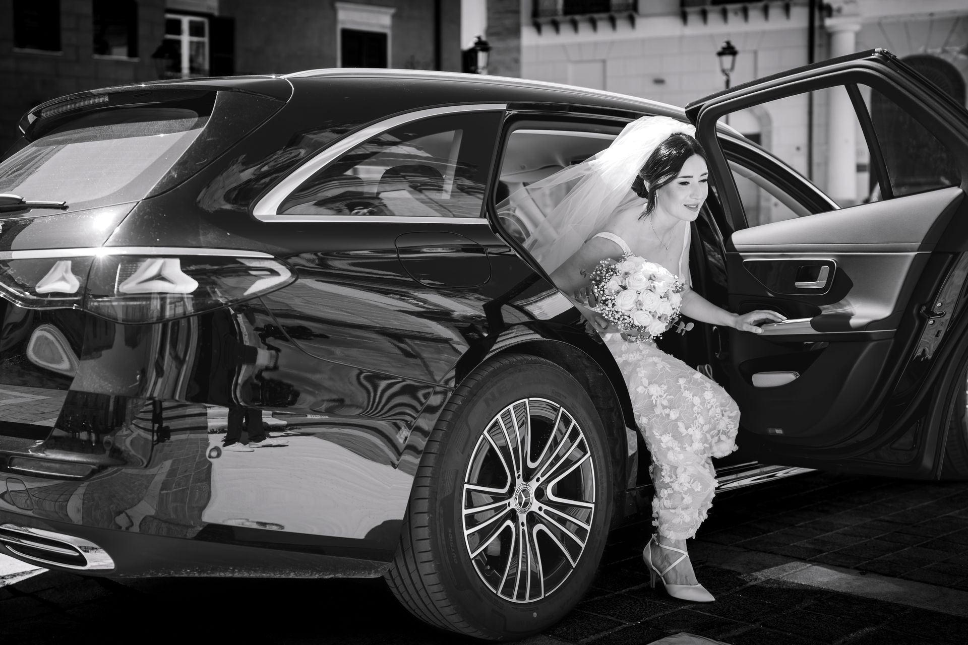 Una foto in bianco e nero di una sposa che esce da un'auto.