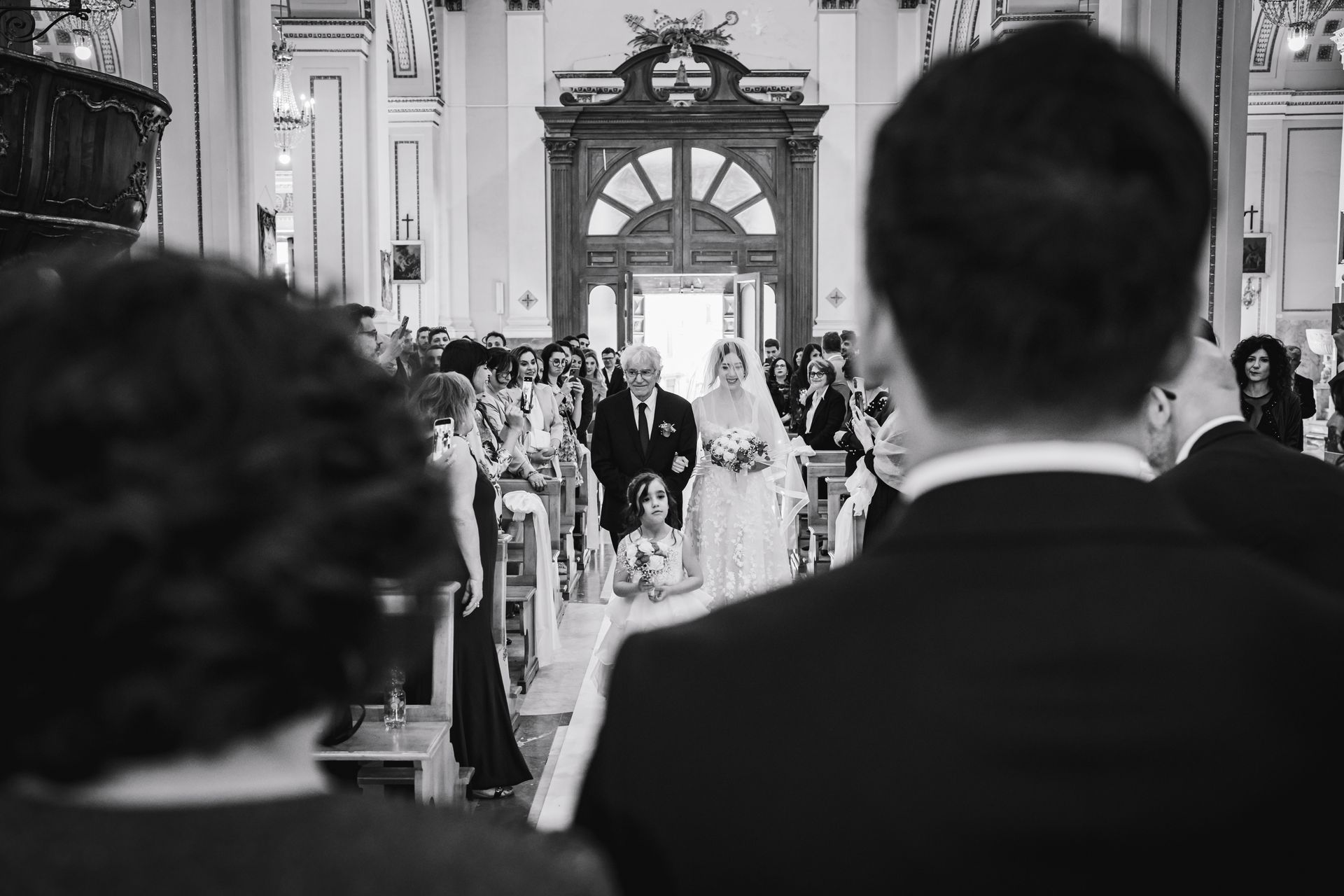 Una sposa e uno sposo stanno camminando lungo la navata di una chiesa.