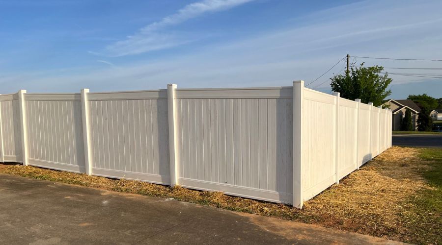 Industrial black steel security fence with outward-curved anti-climb pickets installed as a perimeter boundary for a commercial parking lot.