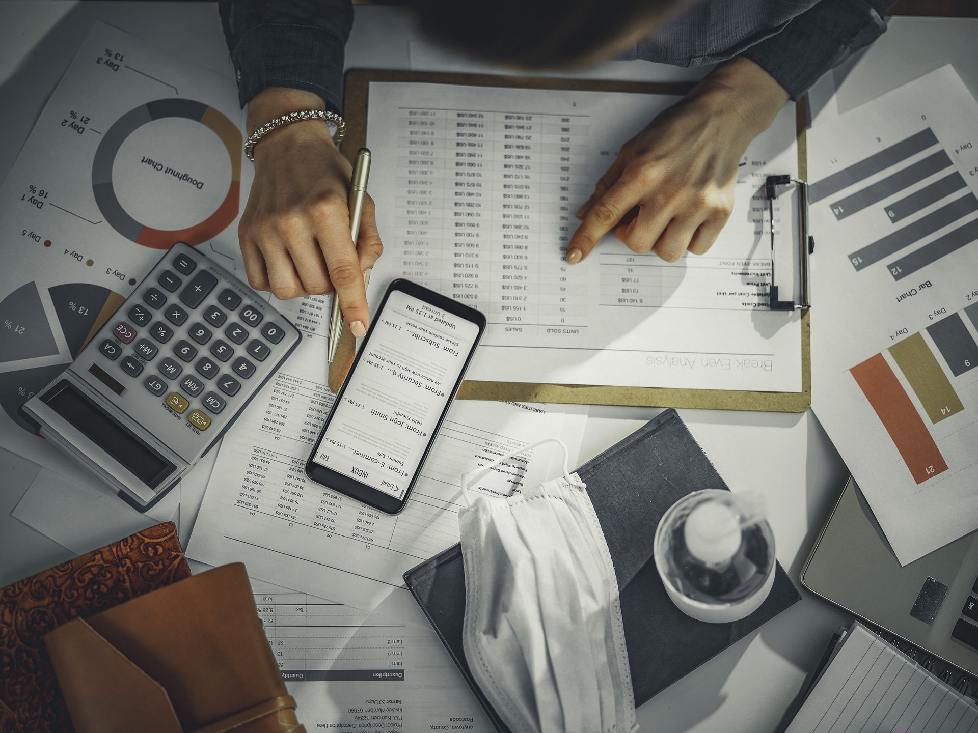 Hands reviewing financial charts with calculator, phone, and documents on a desk