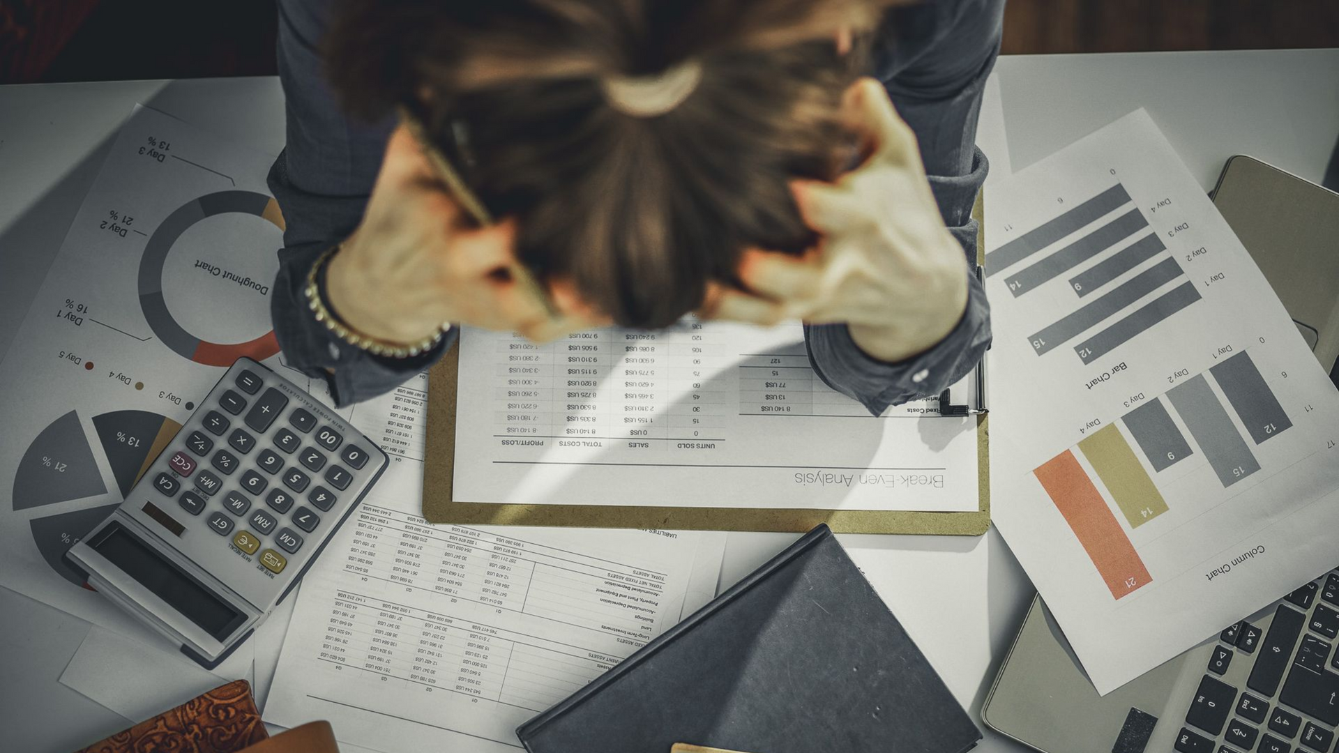 Hands reviewing financial charts with calculator, phone, and documents on a desk