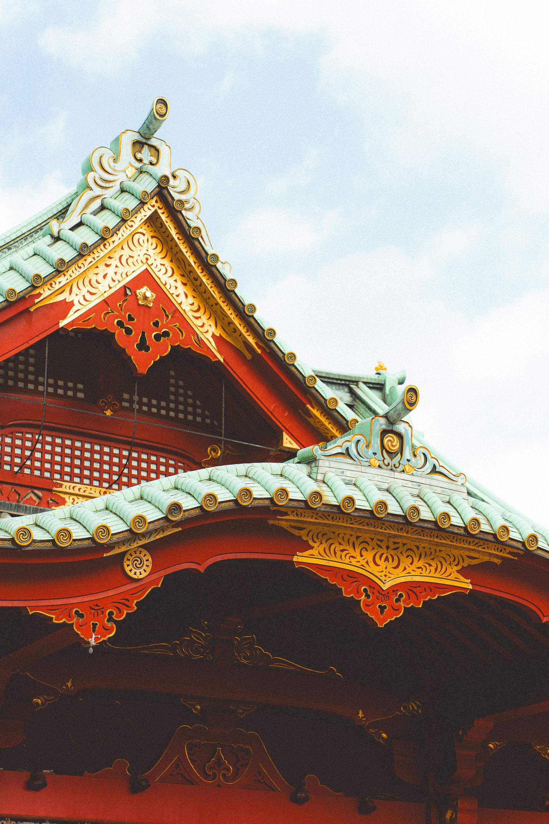 Ornate red-and-gold temple roof with curved eaves against a bright sky