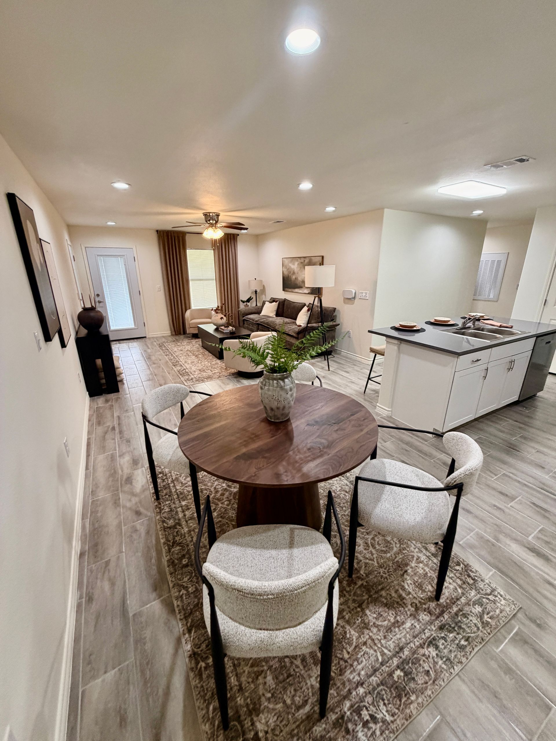 Bright open-concept dining and living room with round table, sofa, and kitchen island.