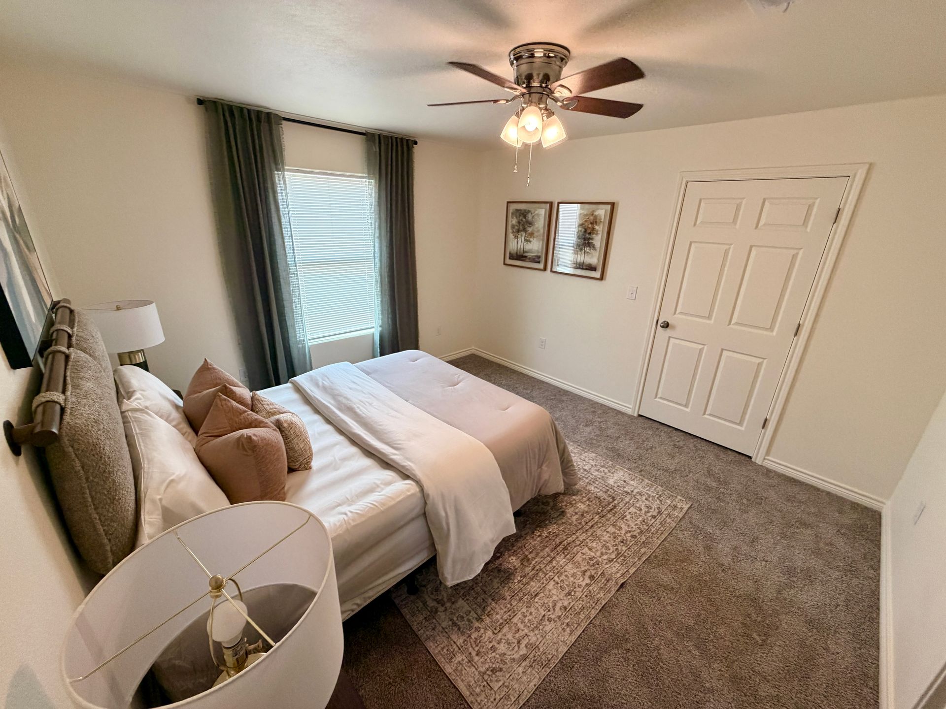 Bedroom with a bed, ceiling fan, window blinds, and neutral carpet and decor.