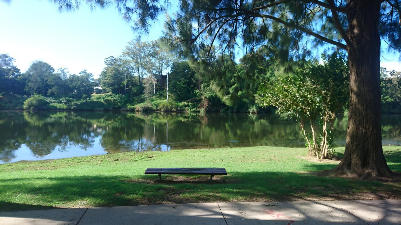 A Picnic Table is Sitting Next to a Lake in a Park — Coastal Test & Tag in Kempsey, NSW