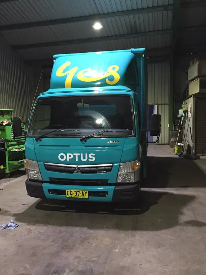 A Teal Optus Truck Parked Inside a Dim Warehouse — Mid North Coast Heavy Vehicle Repairs In Port Macquarie, NSW
