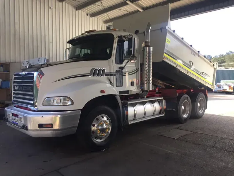 A White Dump Truck With a Raised Bed Parked Inside a Garage — Mid North Coast Heavy Vehicle Repairs In Wauchope, NSW