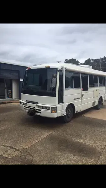A White Shuttle Bus Parked in an Outdoor Paved Lot — Mid North Coast Heavy Vehicle Repairs In Wauchope, NSW