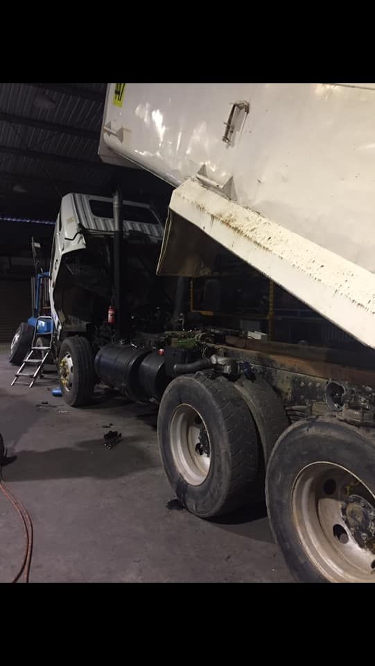 A White Dump Truck With Its Bed Raised in a Dimly Lit Garage — Mid North Coast Heavy Vehicle Repairs In Laurieton, NSW