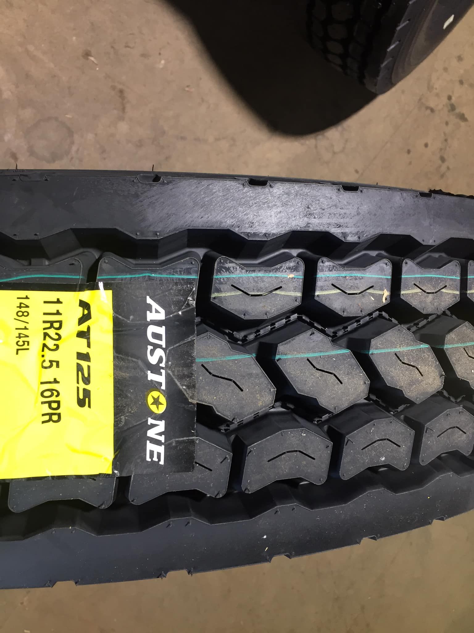 A New Austone AT125 Truck Tire With a Yellow Label — Mid North Coast Heavy Vehicle Repairs In Taree, NSW